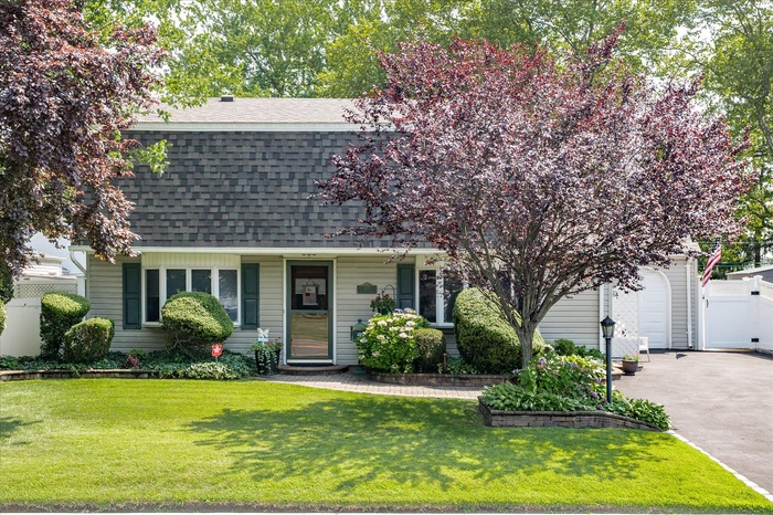 Colonial inspired home featuring roof with shingles, a garage, and driveway