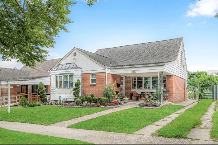 View of front facade featuring a shingled roof, brick siding, and board and batten siding