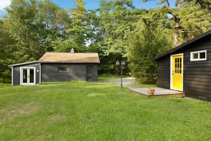 View of green lawn with french doors and an outbuilding