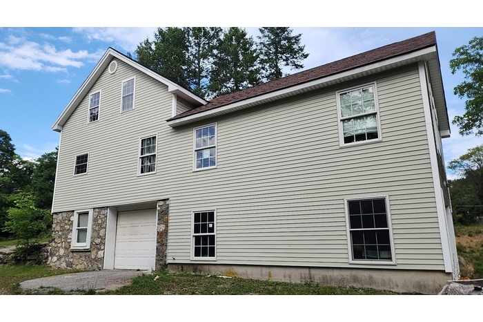 View of home's exterior featuring an attached garage and stone siding
