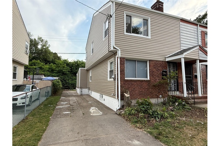 View of front of house featuring a chimney and brick siding