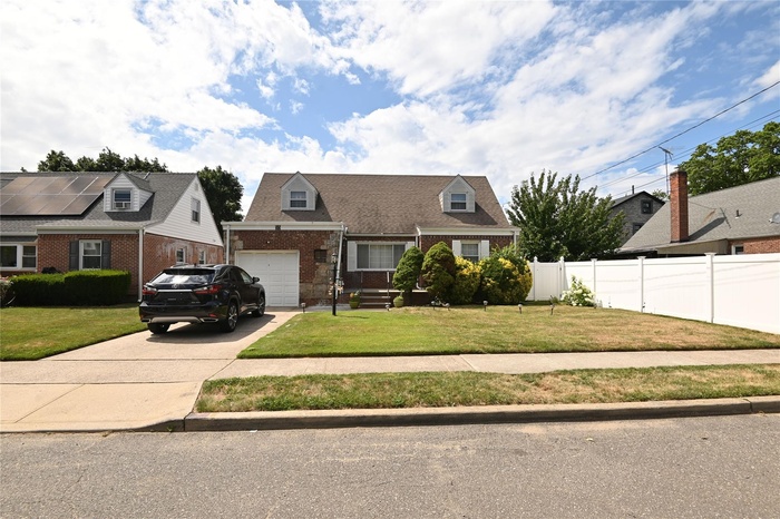 Cape cod house featuring driveway, brick siding, and a garage