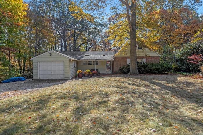 View of front facade featuring a garage, brick siding, driveway, and a front lawn