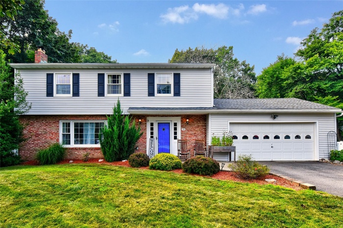 View of front facade with brick siding, asphalt driveway, a front yard, and a garage