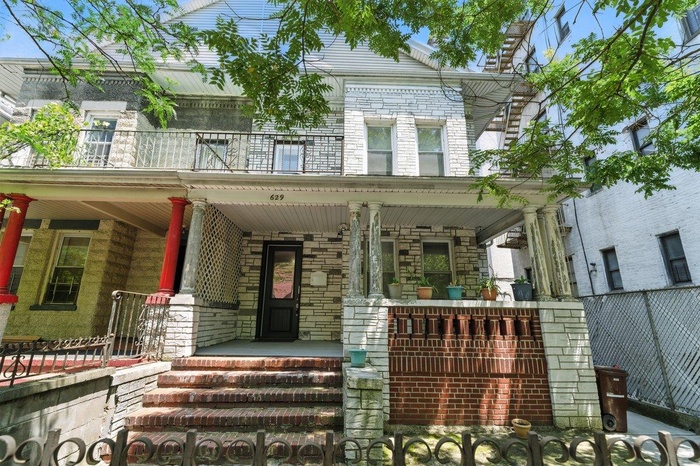 View of front of house with a balcony, a porch, and stone siding