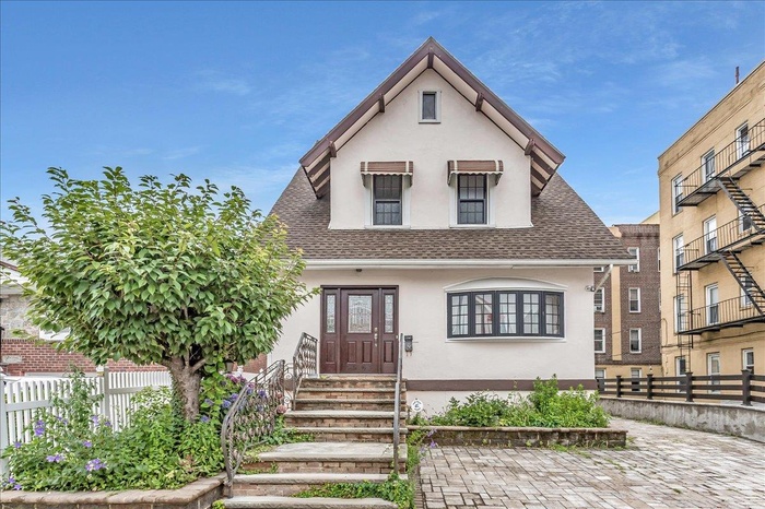 View of front of property featuring stucco siding, entry steps, and roof with shingles