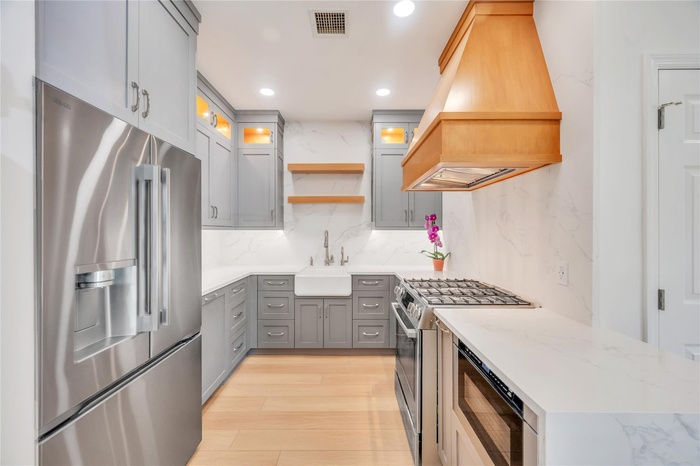 Kitchen featuring open shelves, appliances with stainless steel finishes, gray cabinetry, recessed lighting, and light wood-style floors