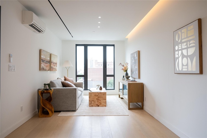 Living room with light wood-style flooring, an AC wall unit, and recessed lighting
