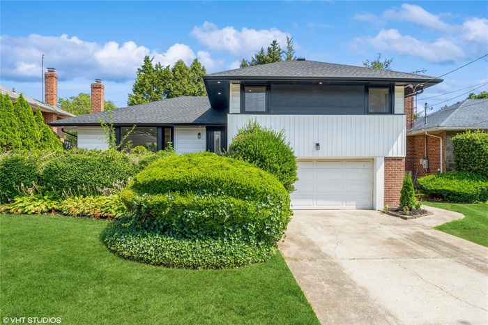Split level home featuring roof with shingles, a front yard, driveway, and a garage