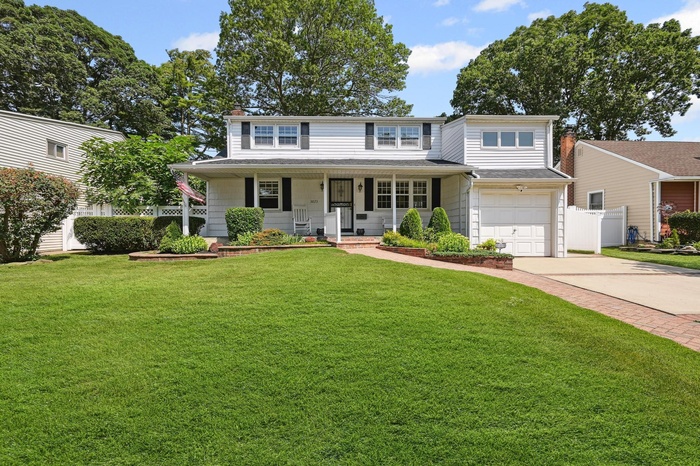 Traditional-style house featuring covered porch, concrete driveway, and an attached garage