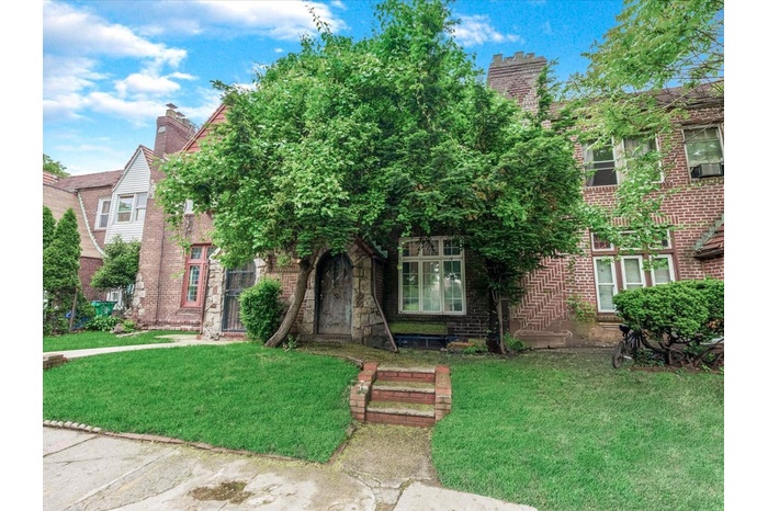 Tudor house with a front yard, a chimney, and brick siding