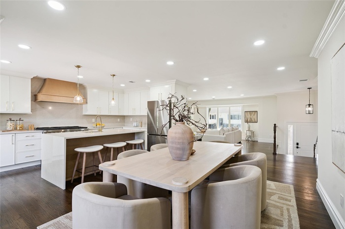 Dining area with dark wood-type flooring, crown molding, and recessed lighting