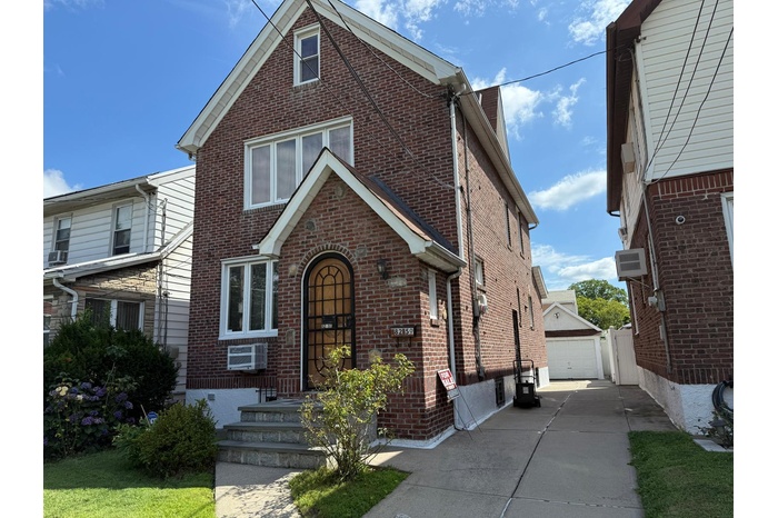 View of front of house featuring brick siding, a garage, and an outdoor structure