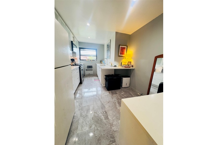 Kitchen featuring freestanding refrigerator, stainless steel gas range oven, white cabinets, light countertops, and range hood