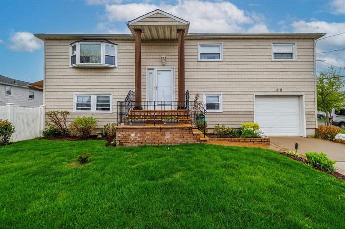 View of front of house featuring a front yard, driveway, a garage, and fence