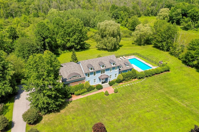 View from above of property with a pool area and a heavily wooded area