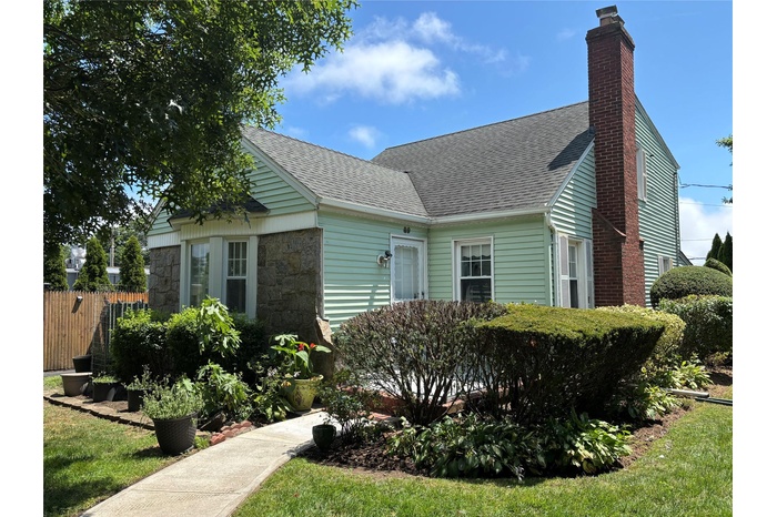 View of home's exterior featuring a shingled roof, a chimney, and stone siding