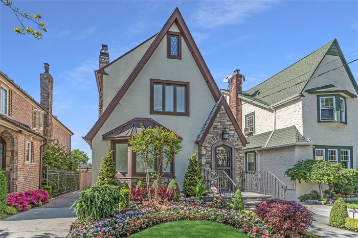 Tudor house with stucco siding, stone siding, and a chimney