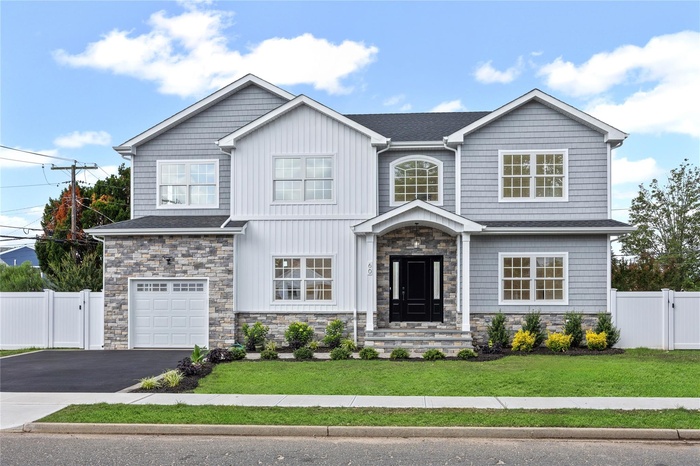 Craftsman-style home with stone siding, driveway, an attached garage, and a gate