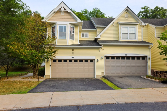 View of front of home with driveway, a garage, and a shingled roof