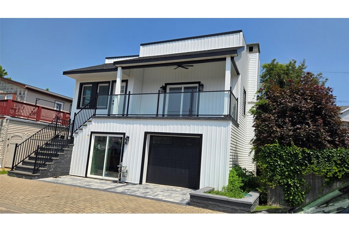 Rear view of house with stairway, a ceiling fan, and a balcony