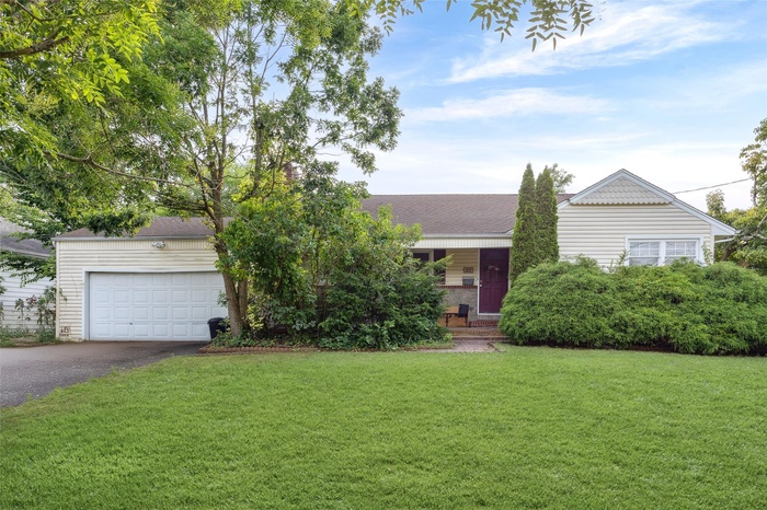 View of front of House featuring driveway, a front lawn, a garage, and a shingled roof