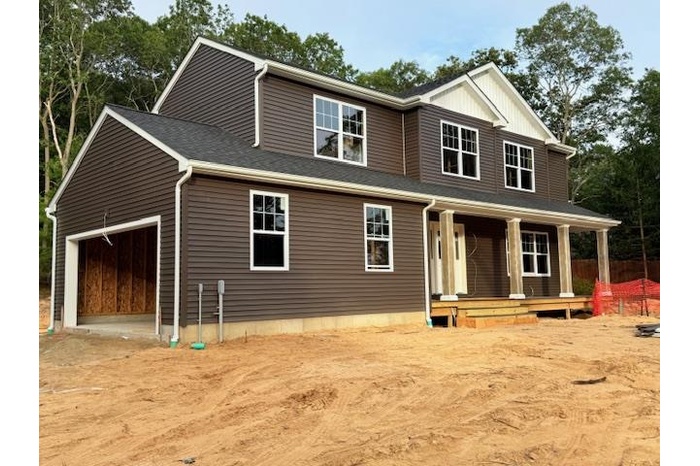 View of front of house featuring a porch, roof with shingles, dirt driveway, and an attached garage