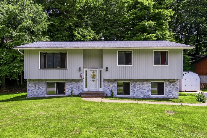 Bi-level home featuring entry steps, a storage unit, and a front lawn