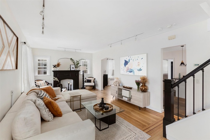 Living room featuring track lighting, stairway, light wood finished floors, and a fireplace