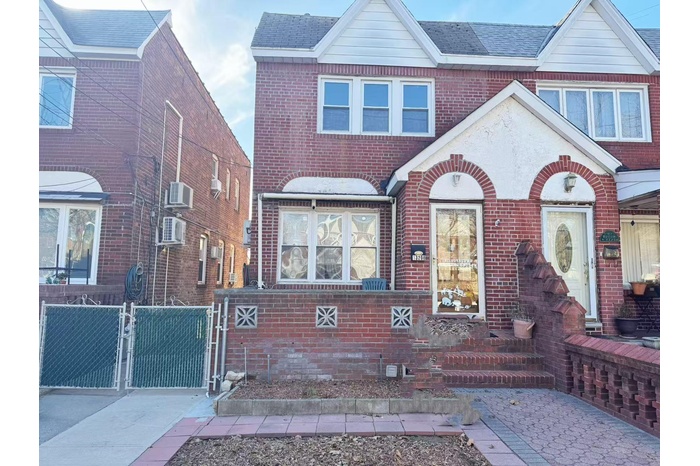 View of front of house featuring a gate, brick siding, fence, and roof with shingles
