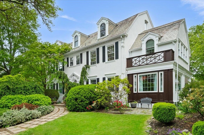View of front of home featuring a balcony, a front lawn, stucco siding, and a high end roof