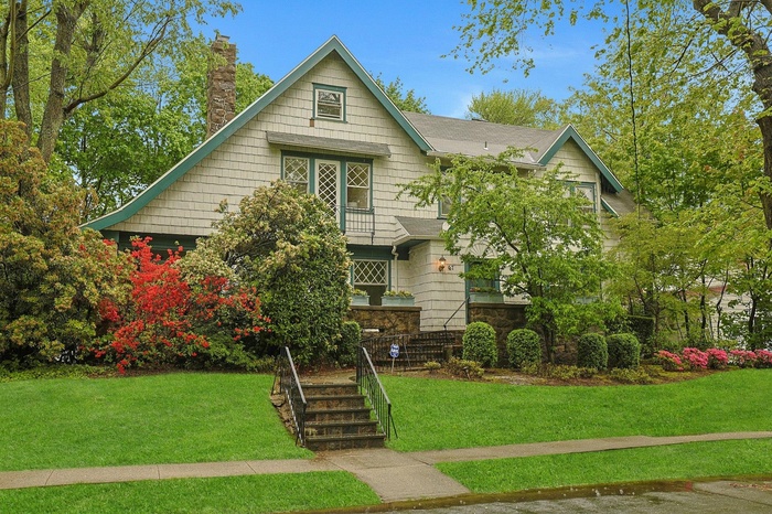 View of front facade featuring a chimney, a front yard, and stone siding