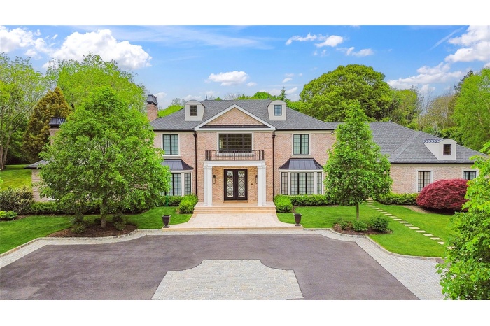 Colonial house with brick siding, french doors, a front yard, a chimney, and a balcony