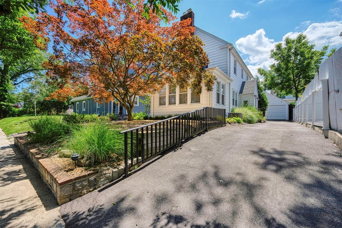 View of front of home with a detached garage, a chimney, and an outbuilding