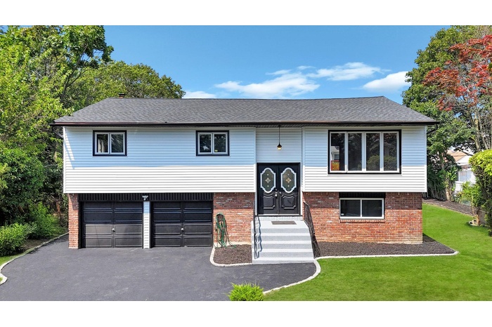 Bi-level home with brick siding, driveway, and a front yard