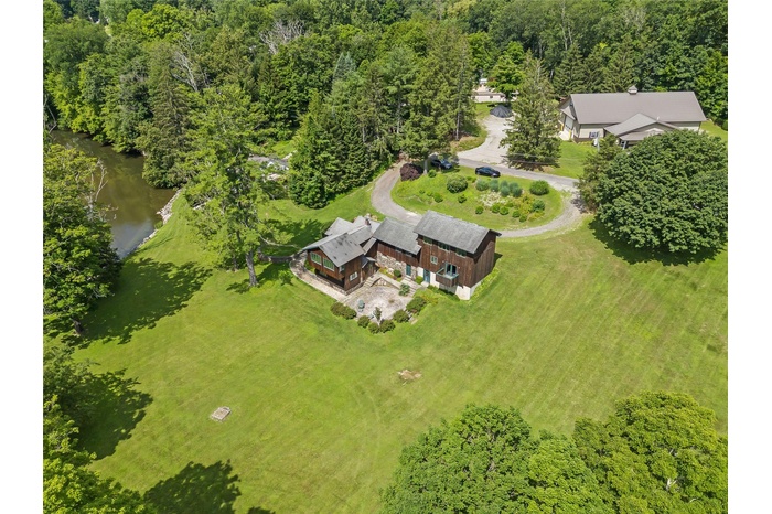 View of subject property featuring a nearby body of water and a heavily wooded area