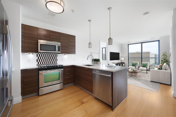 Kitchen with stainless steel appliances, a sink, modern cabinets, open floor plan, and expansive windows