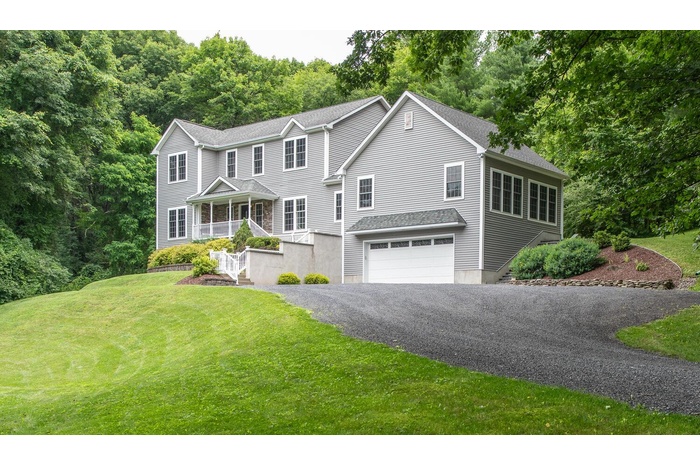View of front facade featuring a front yard, a porch, an attached garage, asphalt driveway, and stairway