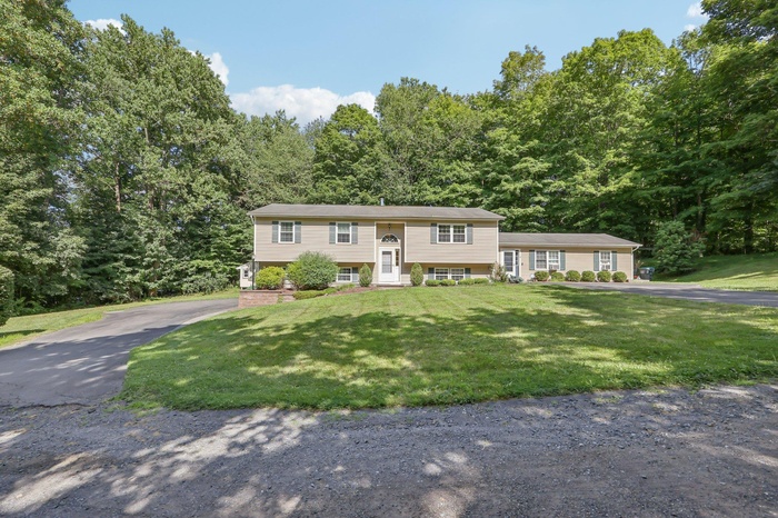Raised ranch with driveway and a front lawn