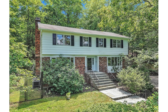 Colonial home with a chimney, brick siding, and a gate