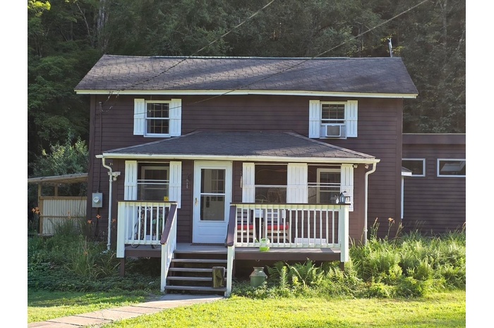 View of front of home with a porch and a forest view