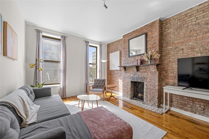 Living area featuring brick wall, wood finished floors, and a fireplace