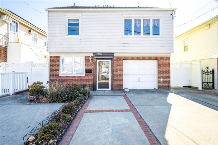 View of front of home with fence, concrete driveway, and brick siding