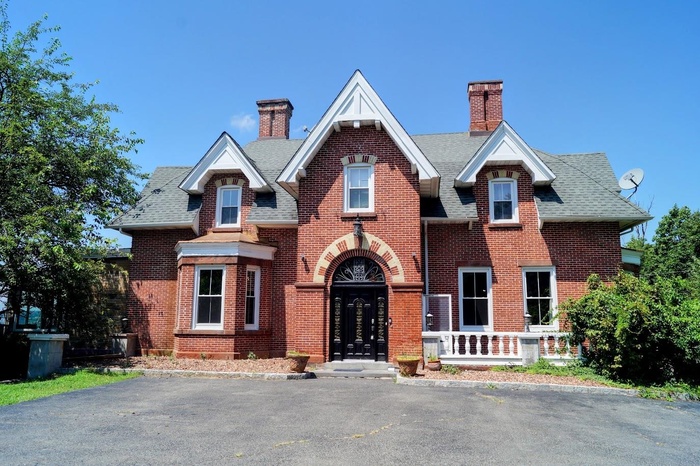 Tudor-style house with a chimney, brick siding, and roof with shingles