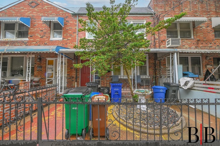 Townhome / multi-family property with brick siding, covered porch, and a fenced front yard