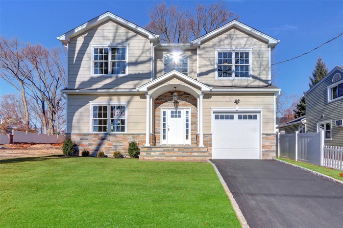 View of front facade featuring a garage and a front lawn