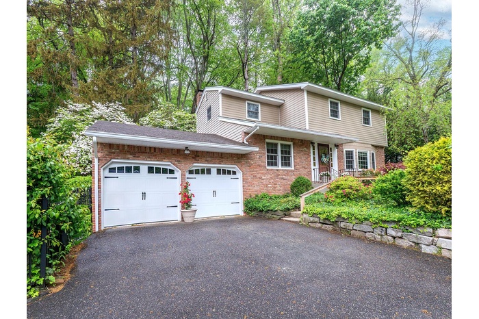 Traditional home with driveway, brick siding, and a garage