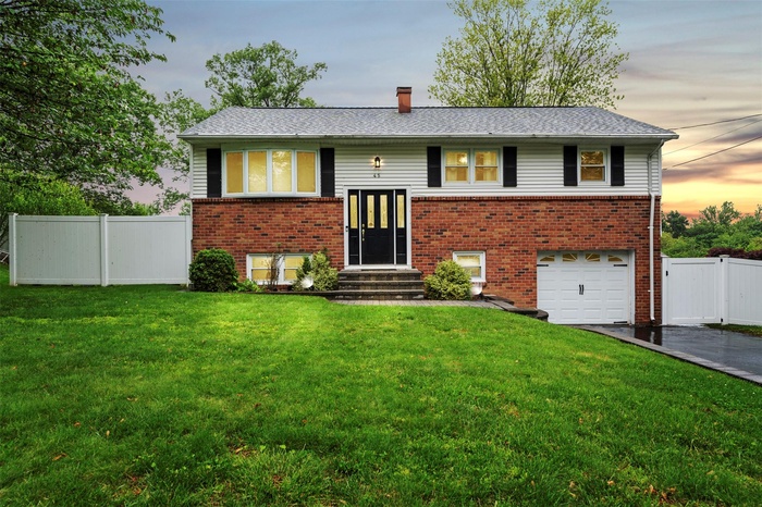 Split foyer home with entry steps, asphalt driveway, an attached garage, and brick siding
