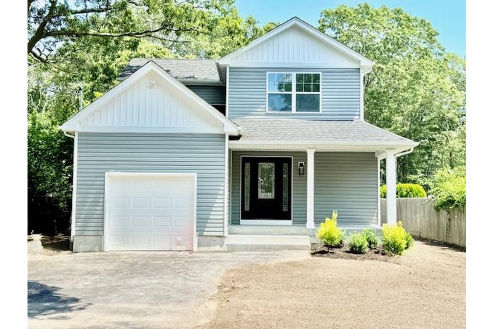 View of front of property featuring concrete driveway, covered porch, board and batten siding, and a shingled roof