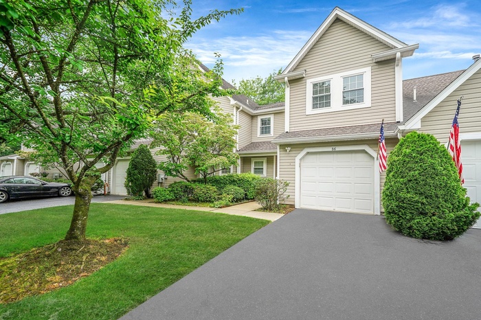 View of front of home with a front yard, a shingled roof, asphalt driveway, and a garage